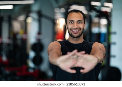 Handsome Smiling Black Man Stretching Arms Before Training In Gym, Closeup Portrait Of Sporty Athletic African American Guy Warming Up His Hands During Workout In Modern Fitness Club, Selective