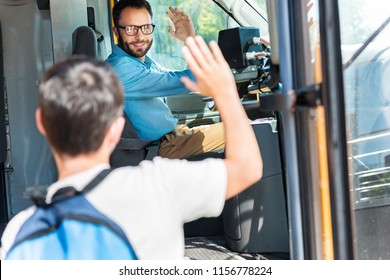 handsome smiling bus driver greeting schoolboy who entering bus