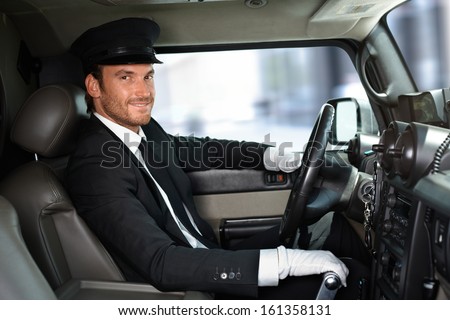 Handsome smiling chauffeur driving limousine.