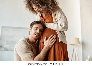 Handsome smiling happy man listening to baby hugging tummy of wife, touching her belly - Powered by Shutterstock