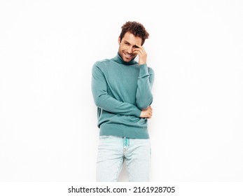 Handsome smiling hipster  model.Sexy unshaven man dressed in summer stylish blue sweater and jeans clothes. Fashion male with curly hairstyle posing in studio. Isolated on white
