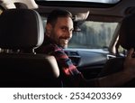 Handsome smiling man driving car and looking over shoulder at back, safety driving concept