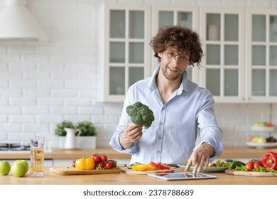 Handsome smiling man in the kitchen preparing vegetable salad, healthy dinner with broccoli, vegan. - Powered by Shutterstock