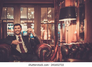 Handsome Smiling Man Sitting With A Cup Of Coffee In A Luxury Interior 