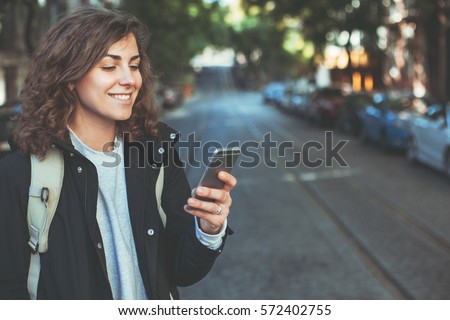Handsome smiling woman with mobile phone walking on the street