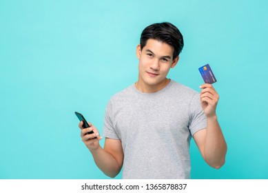 Handsome Smiling Young Asian Man Showing Credit Card For Mobile Payment Concept