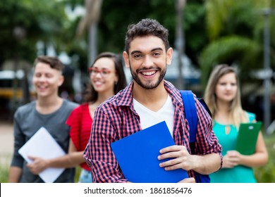 Handsome spanish male student with group of other students outdoor in summer in city