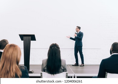 Handsome Speaker Talking During Seminar In Conference Hall And Pointing On Screen