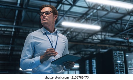 Handsome IT Specialist Using Tablet Computer in Data Center, Looking at the Screen. Succesful Businessman and e-Business Entrepreneur Overlooking Server Farm Cloud Computing Facility. - Powered by Shutterstock