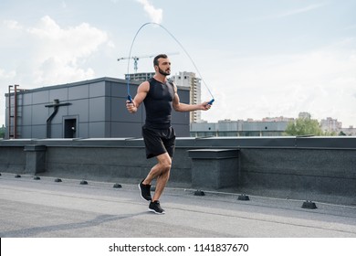 handsome sportsman training with jumping rope on roof - Powered by Shutterstock