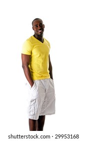 Handsome Sporty African American Man In Yellow Shirt And White Shorts Standing With Hands In Pocket And Big Smile, Isolated