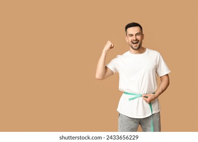 Handsome sporty young man measuring his waist on brown background. Weight loss concept - Powered by Shutterstock