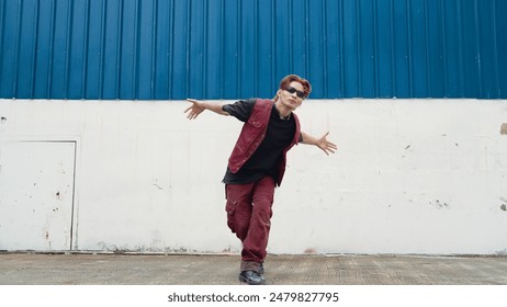 Handsome street dancer practicing break dancing at white back ground. Sport man wearing hip hop style while moving footsteps to music at street with blue background. Outdoor sport 2024. Endeavor. - Powered by Shutterstock