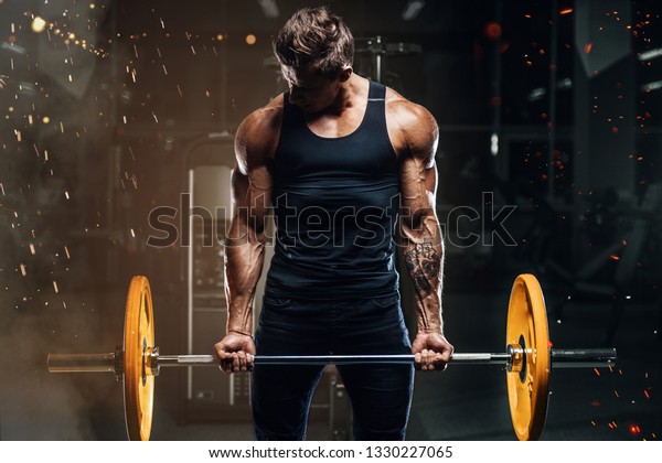 Handsome\
strong athletic fitness men pumping up arm muscles workout barbell\
curl fitness concept background - muscular bodybuilder men doing\
bodybuilding biceps exercises in gym naked\
torso