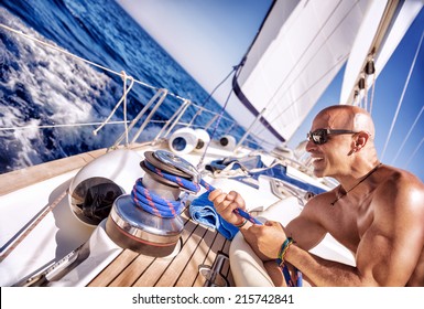 Handsome strong man working on sailboat, sailor enjoys crew duty, luxury holidays, yachting sport activities, sailing the oceans, summer vacation and recreation