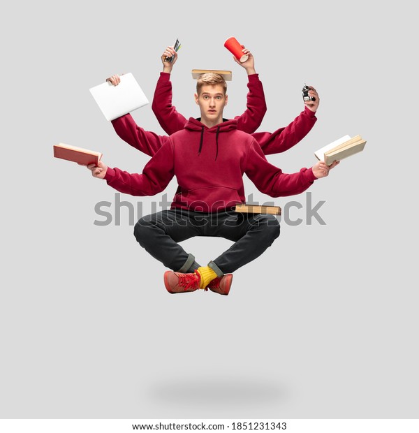 Handsome student, multi-armed man levitating\
isolated on grey studio background with equipment. Concept of\
professional occupation, work, job, education, development.\
Multi-task like Shiva.