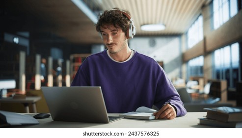 Handsome Student Writing an Essay on Laptop Computer, Thinking About the Topic, Brainstorming, Finding Solutions. Young Stylish Man Studying in a Public Library, Listening to Lecture in Headphones - Powered by Shutterstock