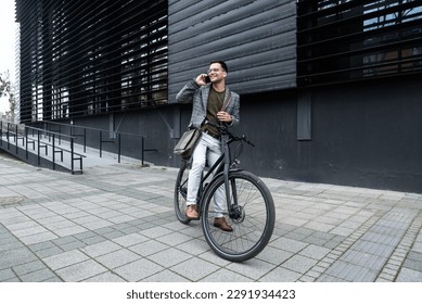 Handsome stylish businessman talking on the phone and driving a bike in the city. Businessperson in front of office building using smartphone on bicycle arrange meeting or date on lunch break - Powered by Shutterstock