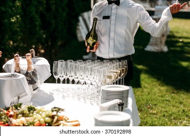 Handsome Stylish Man Bartender Opening  A Bottle Of Champagne In The Street In Celebration Of The Wedding