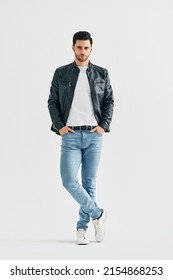 Handsome stylish man portrait on white studio background. Men's beauty concept. Young male wearing jeans, white t-shirt and black leather jacket posing full length