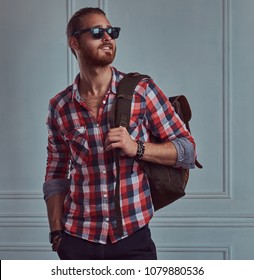 Handsome Stylish Redhead Man In A Flannel Shirt And Sunglasses, Posing In A Studio Against A White Wall.