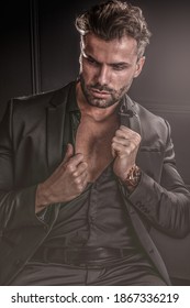 Handsome stylish sexy man in elegant suit, posing on dark black background.