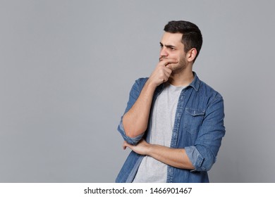 Handsome stylish unshaven young man in denim jeans shirt posing isolated on grey wall background studio portrait. People sincere emotions lifestyle concept. Mock up copy space. Sceptic shocked guy - Shutterstock ID 1466901467