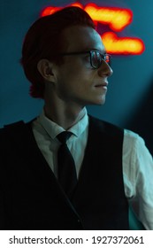 Handsome Stylish Young Man Model With Glasses In Fashion Business Clothes With Suit And Tie In A Bar With Red And Blue Light