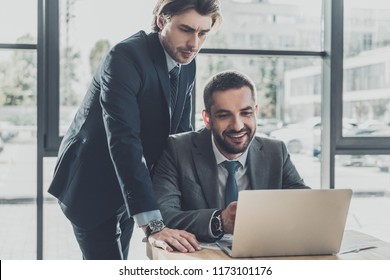 handsome successful business people working with laptop together at modern office - Shutterstock ID 1173101176