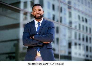 Handsome successful businessman standing with arms folded outside next to financial buildings, possible CEO, entrepreneur, corporate professional