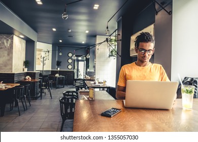 Handsome and successful indian man freelancer work laptop in cafe. Freelance and remote work.