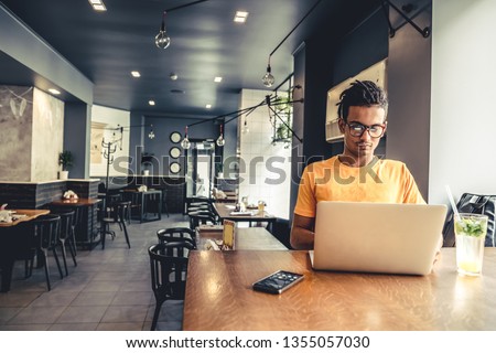 Handsome and successful indian man freelancer work laptop in cafe. Freelance and remote work.