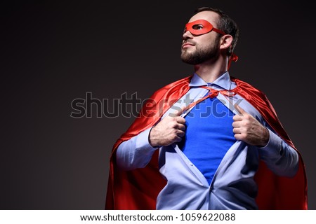 handsome super businessman in mask and cape showing blue shirt and looking away isolated on black