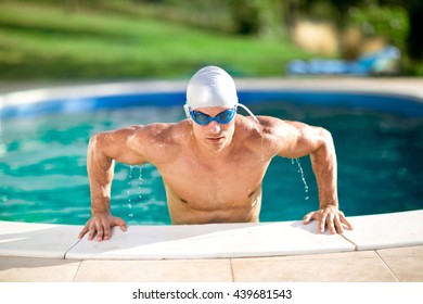 Handsome swimmer with cap and goggles in swimming pool 