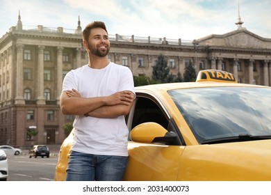 Handsome taxi driver near car on city street