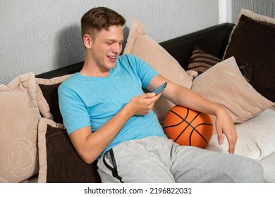 Handsome Teen Holding Smartphone And Basketball Ball In His Room, Live Stream Concept