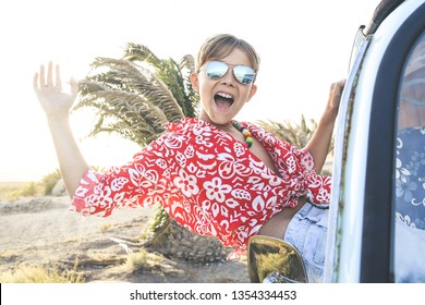 Handsome teenage boy with sunglasses greets shouting cheerfully out the window of the vintage van dressed as a flower child hippie. Concept of freedom and lighthearted holiday, free time traveling - Powered by Shutterstock