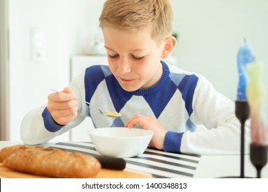 Handsome Teenager Eating Soup And Whole Grain Bread In Bright Living Room At Home