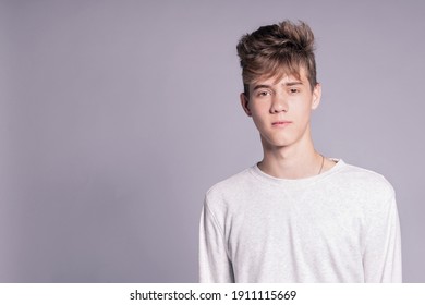 Handsome teenager guy 16-18 years old over gray background. Close up portrait of caucasian young man
