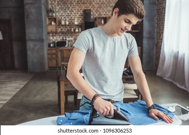 Handsome Teenager Ironing Blue Shirt With Iron