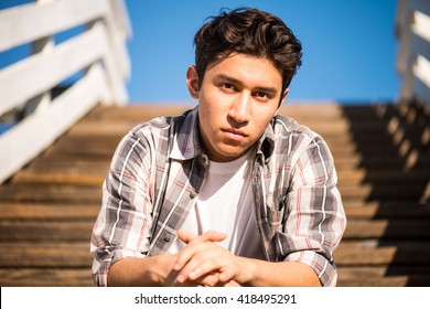 Handsome teenager outdoors, sitting on steps, thinking