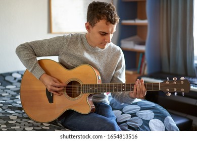 Handsome Teenager Playing At Guitar In His Room