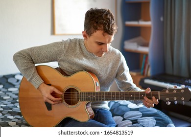 Handsome Teenager Playing At Guitar In His Room