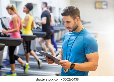 Handsome Trainer Looking At Clipboard At The Gym