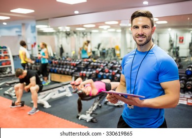 Handsome trainer using tablet in weights room at the gym