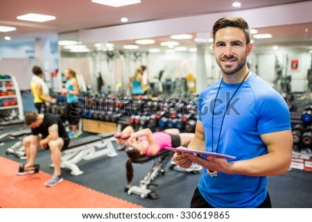 Handsome trainer using tablet in weights room at the gym