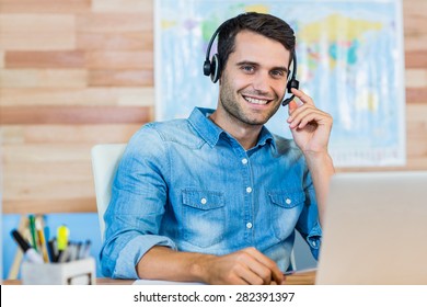 Handsome travel agent smiling at camera in the office