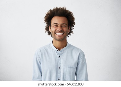 Handsome unshaven young dark  skinned male laughing out loud at funny meme he found internet  smiling broadly  showing his white straight teeth  Positive human facial expressions   emotions