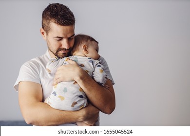 Handsome unshaven young father holding his only beloved son and putting him to sleep. It's noon nap time. - Shutterstock ID 1655045524