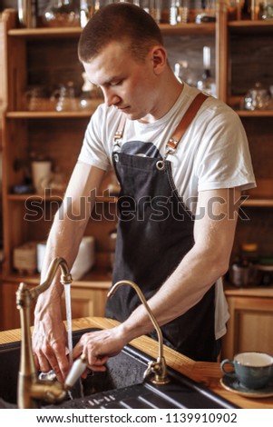 a handsome waiter is washing a cup at the restaurant. close up photo